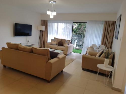 uma sala de estar com dois sofás e uma televisão em Astoria Luxury Apartments, Lavington em Nairobi