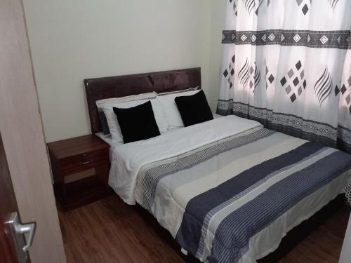 a bedroom with a bed with a black and white comforter at Waridi Apartments in Nairobi