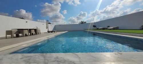 a swimming pool in front of a building with a white wall at villa zak in Midoun