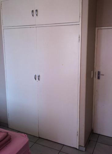 a white closet with two doors in a room at Room Blue in Pretoria