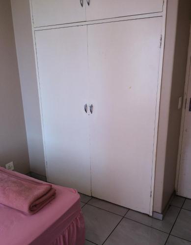 a white cabinet in a room with a pink bed at Room Blue in Pretoria