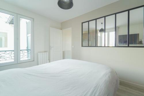 a white bedroom with a large bed and windows at Quiet cosy and bright apartment with Terrace in Saint-Ouen