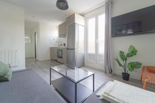 uma sala de estar com uma mesa de vidro em frente a um frigorífico em Quiet cosy and bright apartment with Terrace em Saint-Ouen