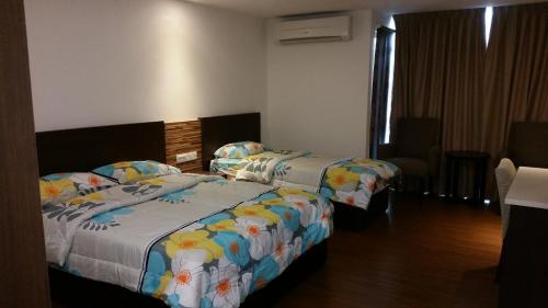 a hotel room with two beds and a chair at Kota Bharu Apartment in Kota Bharu