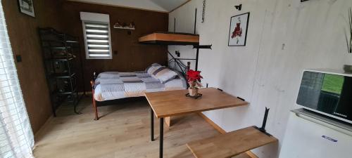 a small bedroom with a bed and a table with a television at Les Milles Bottes et ses Roulottes in Encausse-les-Thermes