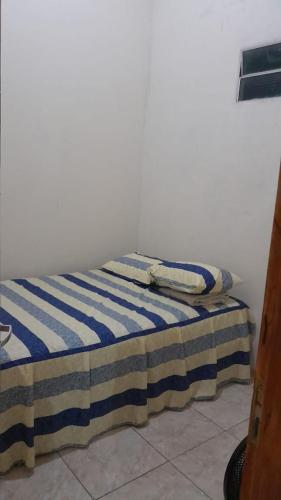 een bed met een blauwe en witte gestreepte deken erop bij Hospedagem Domiciliar in Viçosa do Ceará