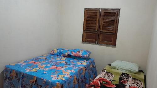 a bedroom with a bed with a blue sheets and a window at Hospedagem Domiciliar in Viçosa do Ceará