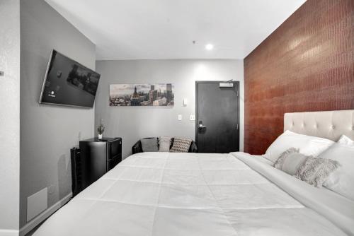 a bedroom with a large white bed and a tv at Good Hotels Downtown Denver in Denver