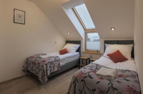a attic bedroom with two beds and a window at Apartamenty pokoje Jasna in Augustów