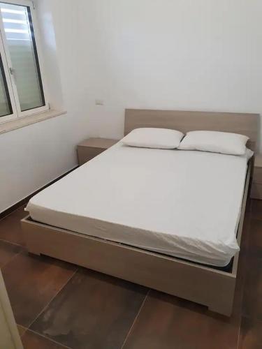 een groot bed in een kamer met een raam bij Appartamento Concio in Policoro