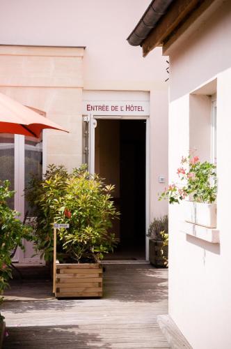 an entrance to a hotel with plants and an umbrella at Hôtel Moderne in Gisors