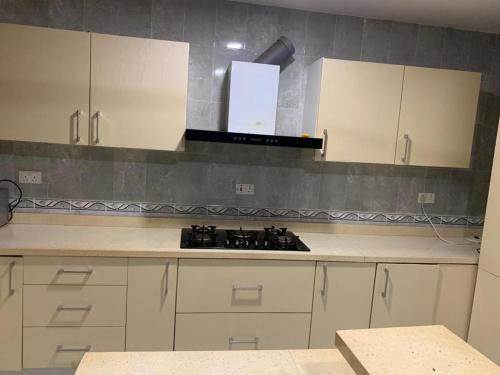 a kitchen with white cabinets and a stove in it at Self contained Master Bedroom Apartment in Tema in Tema