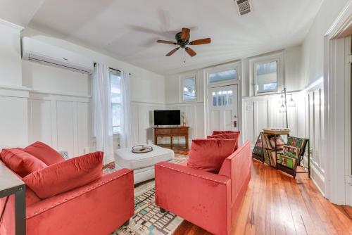 a living room with two red chairs and a ceiling fan at Baton Rouge Cottage with Fenced Yard Near Downtown! in Baton Rouge