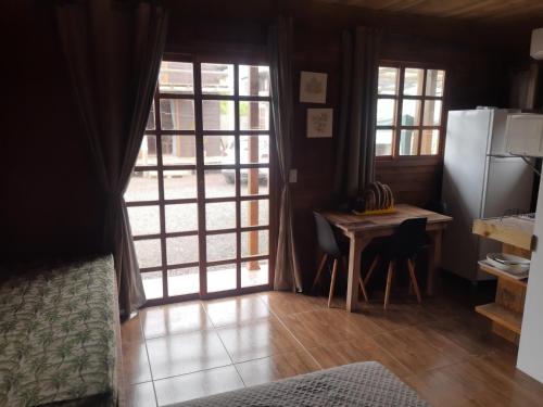 a kitchen with a table and a refrigerator at Chalé do Budha in Torres