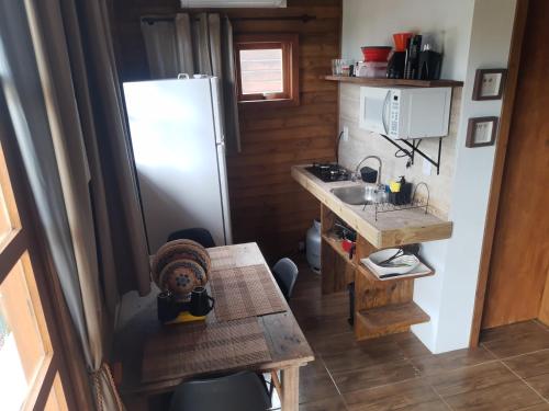 a small kitchen with a refrigerator and a table at Chalé do Budha in Torres