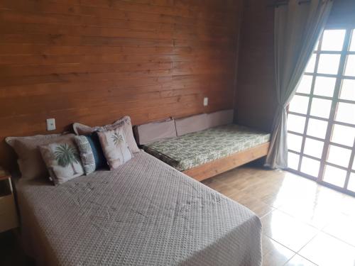 um pequeno quarto com uma cama e uma janela em Chalé do Budha em Torres