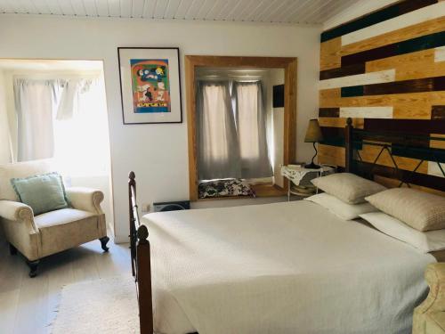 a bedroom with a large white bed and a chair at Casinhas da Calçada de Santiago - pet friendly, garage and with stairs in Tomar