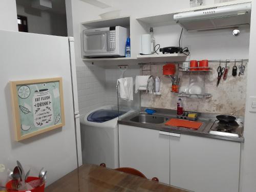 una pequeña cocina con fregadero y microondas en Terrazzas 305 - Beira-Mar AR Wi-Fi Lavadora 02 camas de casal, en João Pessoa