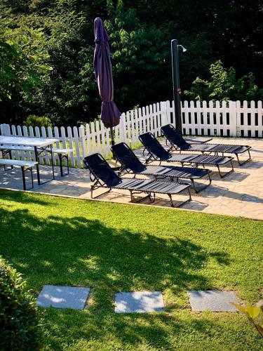 a group of chairs and an umbrella next to a fence at Odisea Hill House - Modern Holiday Home with swimming pool, sauna, jacuzzi, WiFi and 2 bedrooms, near Varazdin in Gačice