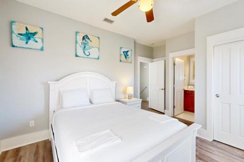 une chambre avec un lit blanc et un ventilateur de plafond dans l'établissement Barefoot Cottages #B48, à Highland View