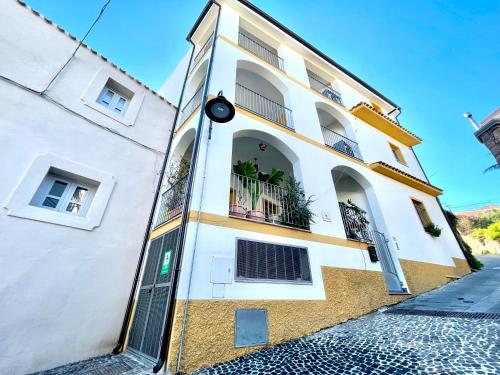 a white and yellow building with a balcony at Le Corti Sarde Apartments in Bari Sardo