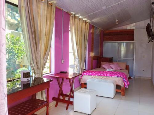 1 dormitorio con paredes rosas, 1 cama y 1 mesa en KORYARES HAUS-TAMBOPATA en Puerto Maldonado
