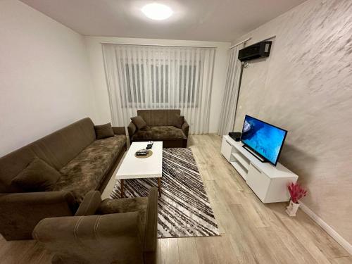 a living room with a couch and a tv at Lovely Family Apartment in Ferizaj