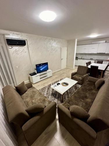 een woonkamer met een bank en een tafel bij Lovely Family Apartment in Ferizaj