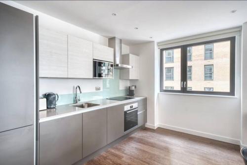 a kitchen with white cabinets and a large window at Luxurious 2 Bedroom Central Flat in Leicester