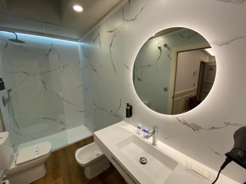 a white bathroom with a sink and a mirror at Hotel Boutique Atrio in Valladolid