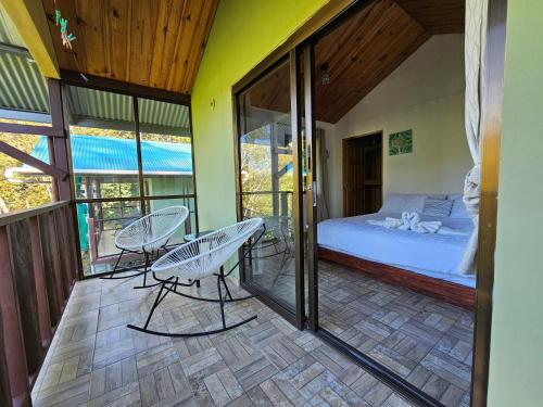 Habitación con balcón con 1 cama y sillas. en Eco Horqueta en Boquete