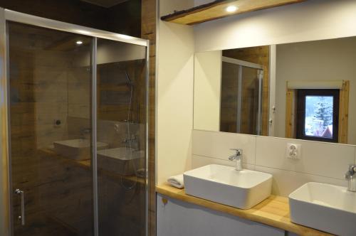 a bathroom with two sinks and a shower and a mirror at Cataleya Rajcza in Rajcza