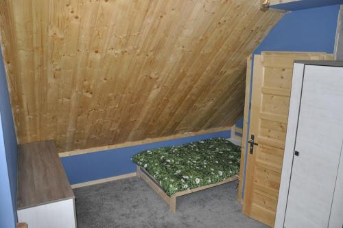 a small room with a bed and a wooden ceiling at Cataleya Rajcza in Rajcza