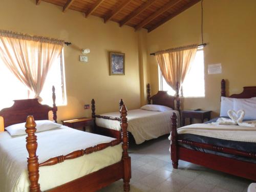 a bedroom with two beds and two windows at Hotel Tahami in Sonsón