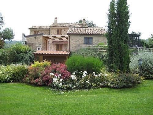 a house in a yard with flowers and plants at Cascina del Poeta in Recanati