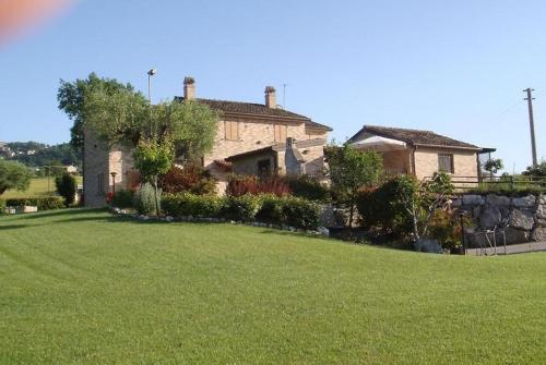 une grande maison avec une pelouse verte en face de celle-ci dans l'établissement Cascina del Poeta, à Recanati