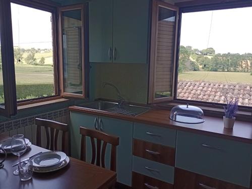 a kitchen with a table and a sink and two windows at Cascina del Poeta in Recanati