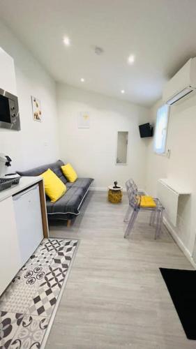sala de estar con sofá negro y almohadas amarillas en Charmant studio près de Roissy CDG, en Le Mesnil-Amelot