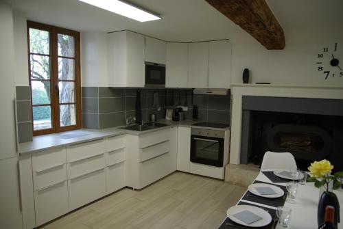 une cuisine avec des placards blancs et une cheminée dans l'établissement Ancienne ferme rénovée dans le Gers, à Béraut