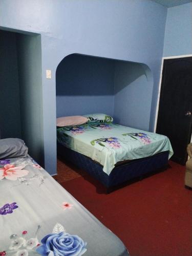 two twin beds in a room with blue walls at Hotel 24 /7 in Comayagua