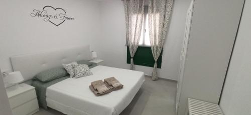 a small white bedroom with a bed and a window at PARAISO DE LUX in Costa de Antigua