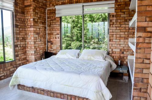 1 dormitorio con 1 cama grande en una pared de ladrillo en Rancho Grande, en Silvania