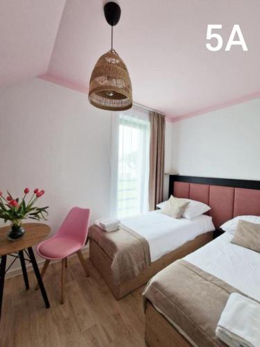 a hotel room with two beds and a pink chair at Słoneczne Zacisze Las obok Zatora in Las