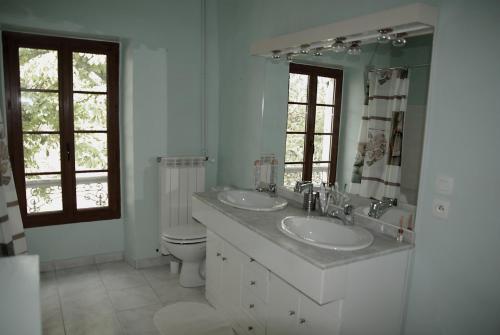 La salle de bains blanche est pourvue de 2 lavabos et de toilettes. dans l'établissement Ancienne ferme rénovée dans le Gers, à Béraut