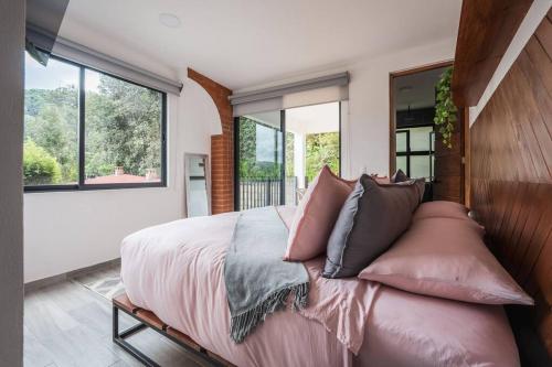 a bedroom with a large bed with pink pillows at La Fábrica #5 Saint Gobain in Valle de Bravo