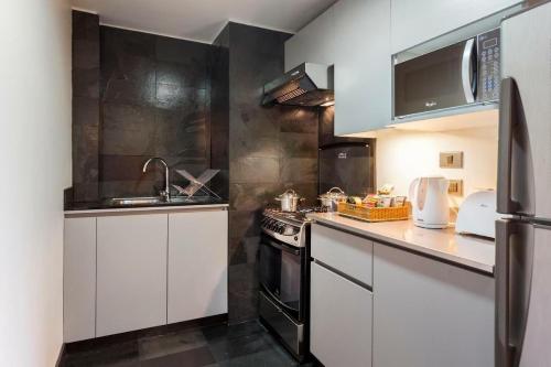 a kitchen with white cabinets and a sink and a stove at Suites El Golf San Sebastian 2711 Las Condes in Santiago