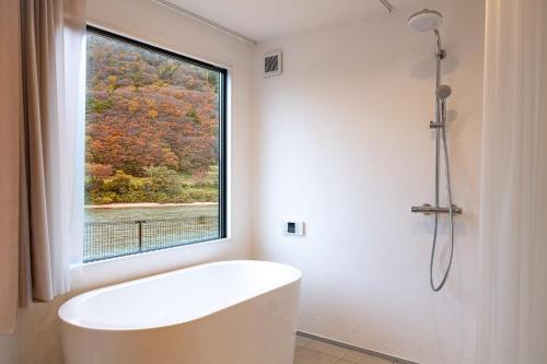 ein Bad mit einer weißen Badewanne und einem Fenster in der Unterkunft R;MOGAMI - Vacation STAY 25467v 