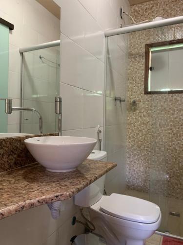 a bathroom with a sink and a toilet and a shower at Pousada Recanto do Chalé Ltda in Macacos