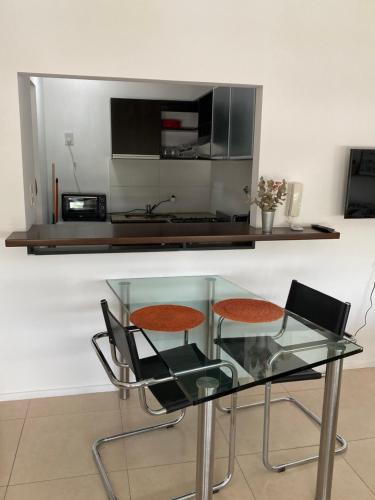 a glass table with two chairs and a microwave at Terrazas Resort monoambiente moderno con piscina in La Plata
