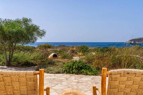 two chairs sitting on a beach with the ocean in the background at House of Harmony - Beachfront in Antiparos